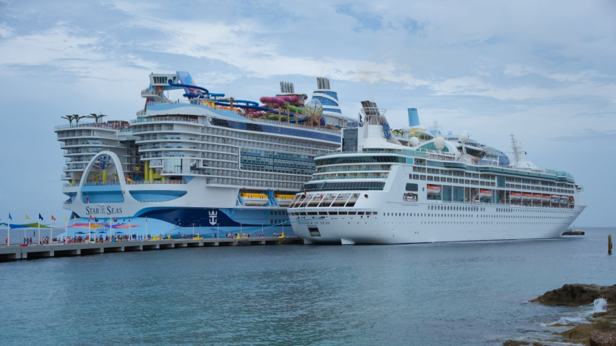 A large family cruise ship sails through the Caribbean near a tropical island.