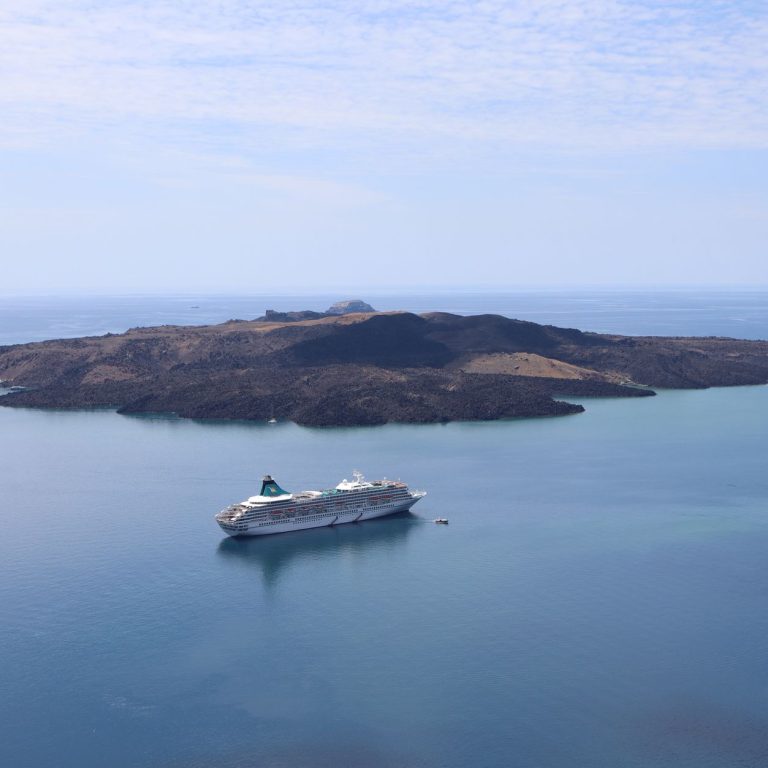Cunard cruise ship sailing near a Greek island coastline