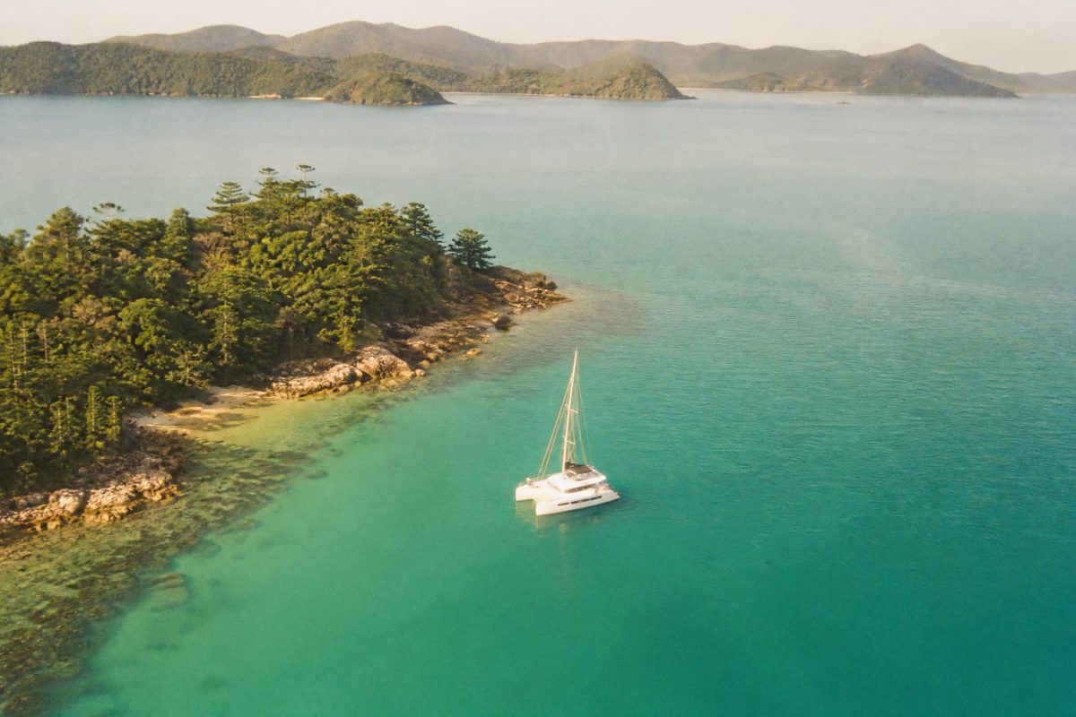 Small luxury sailing catamaran anchored in a quiet bay in the Whitsunday Islands